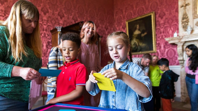 Two children look at notecards as they take part in an activity inside Sudbury Hall